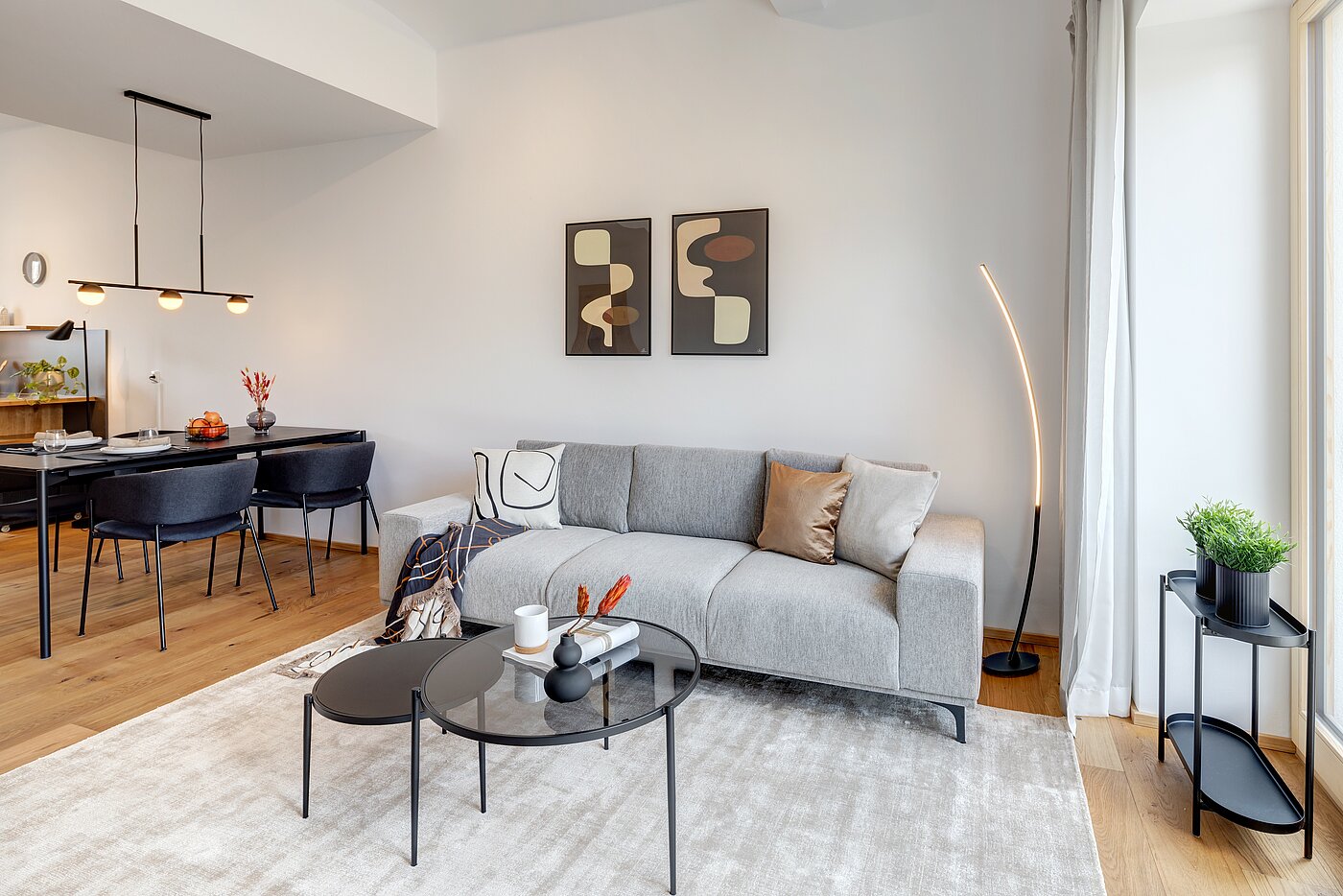 Zu sehen ist ein Sofa mit Beistelltisch und links ein Esstisch mit vier Stühlen
