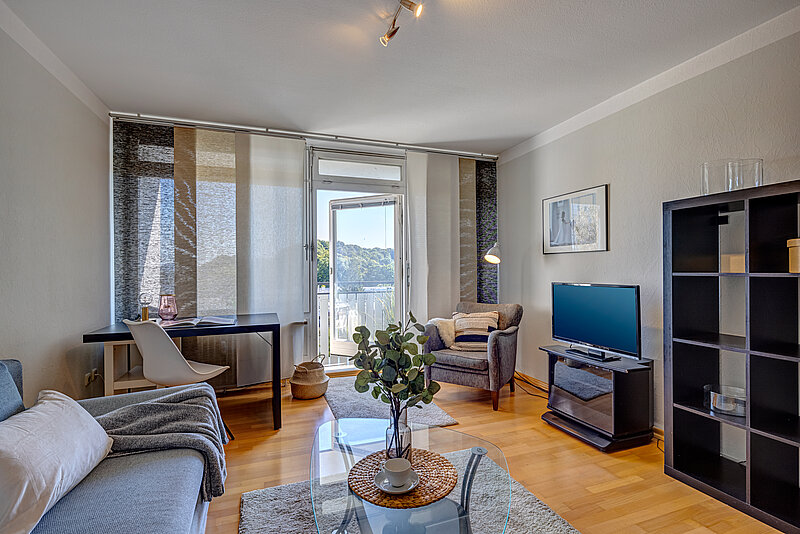 Wohnzimmer nachher Durch helle Kissen und Decken sowie einem neuen Flachbildfernseher wirkt der Raum moderner.