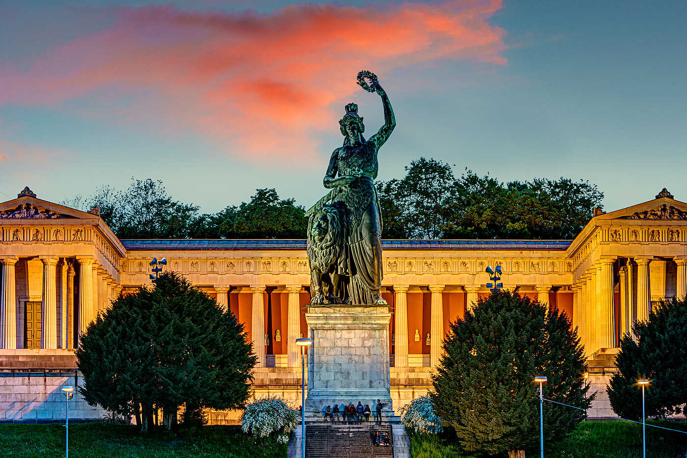 Zu sehen ist die Statue der Bavaria, im Hintergrund ein pinker Sonenuntergang