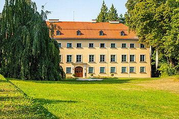 Zu sehen ist ein Gebäude in Ismaning mit grüner Wiese im Vordergrund