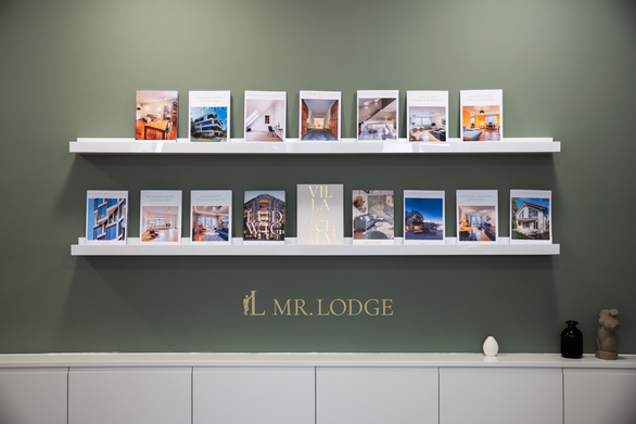 Mr. Lodge Büro München – Magazinwand mit Immobilien-Exposés zum Immobilienverkauf