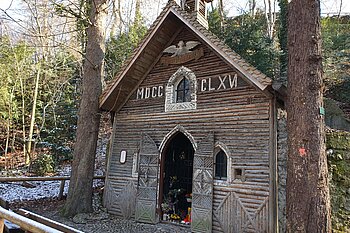 Das Bild zeigt ein Holzhaus "Marienklause" umgeben von Bäumen