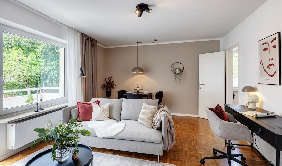 Wohnzimmer mit Sofa, Schreibtisch und Esstisch für zwei