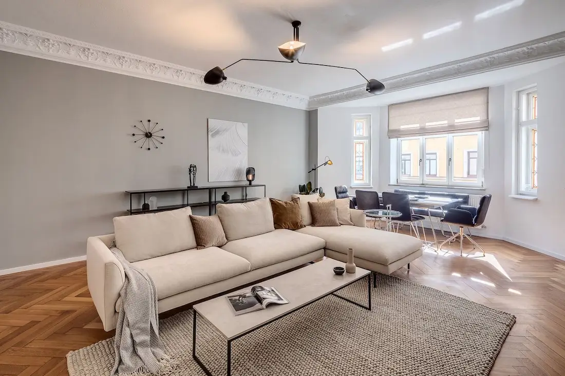 Großzügiges Altbau-Wohnzimmer mit Stuckdecke, Sofa und Essbereich