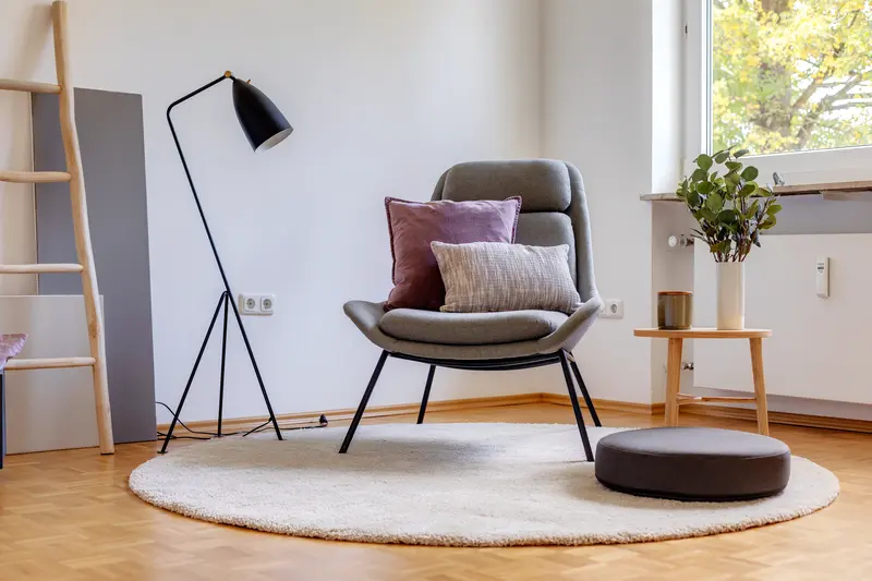 Wohnzimmer nach Home Staging mit Designsessel, Stehlampe und hellem Teppich