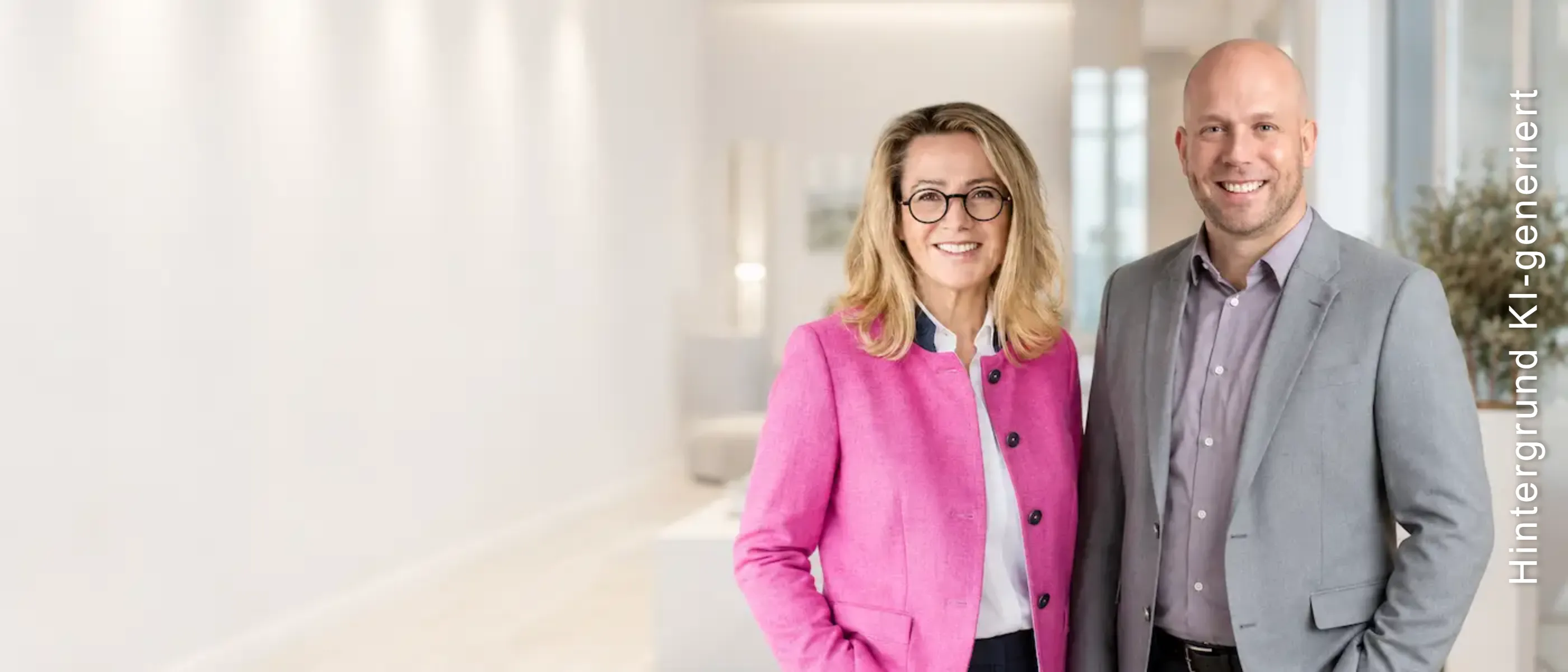 Petra und Alexander, Immobilienmakler am Tegernsee, lächeln in einem hellen Wohnraum