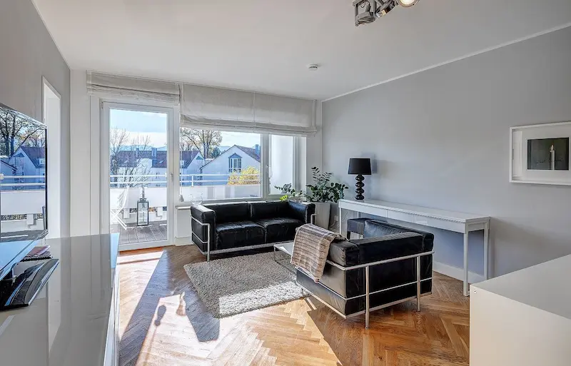 Heller Wohnbereich mit Ledersofas, Fischgrätparkett und Arbeitsplatz am Fenster
