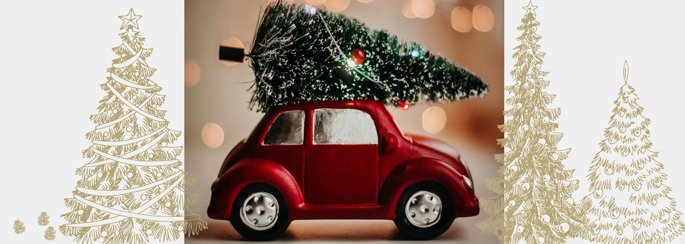 Auf dem Bild ist ein kleines rotes Auto mit einem Weihnachtsbaum auf dem Dach zu sehen